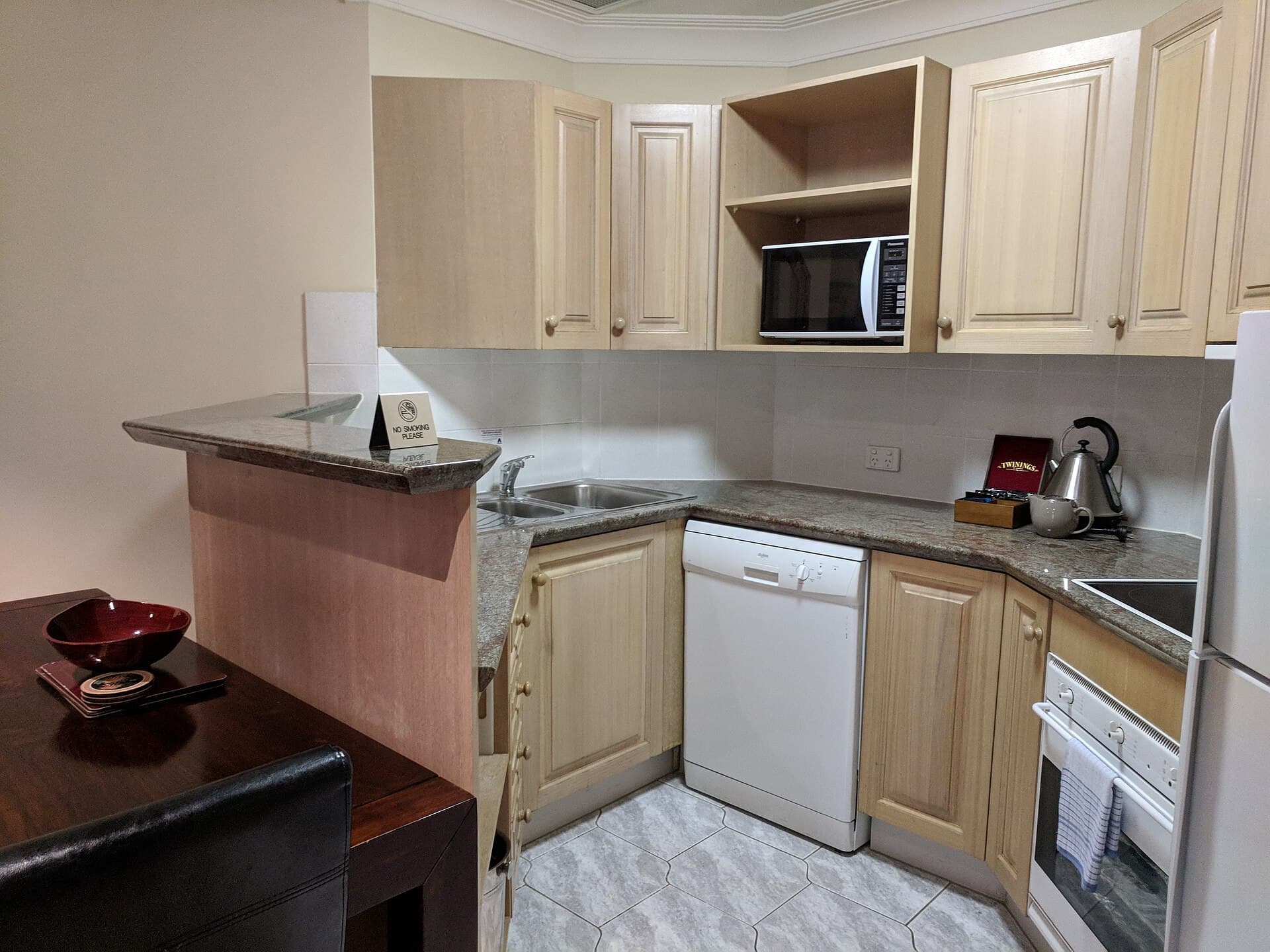 A kitchenette inside an apartment-hotel room, with a hob, sink and dining table