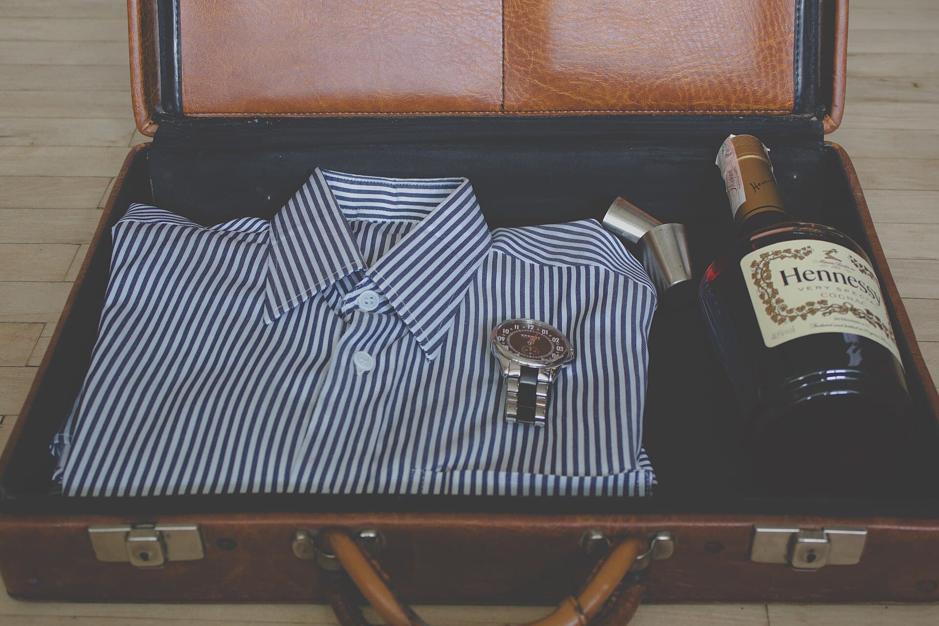 An open suitcase packed with folded clothes on a bed